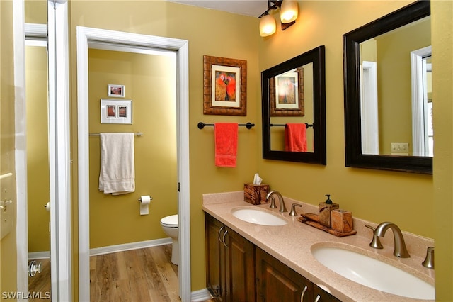 bathroom featuring hardwood / wood-style flooring, dual vanity, and toilet