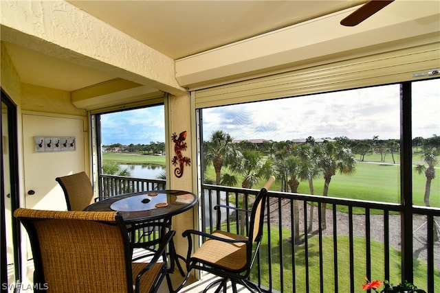 sunroom featuring a water view and ceiling fan