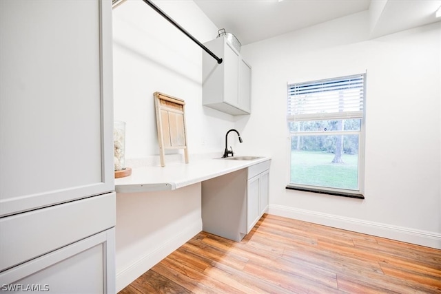 interior space featuring built in desk, sink, and light wood-type flooring