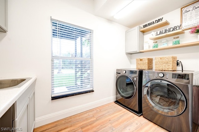 clothes washing area with light hardwood / wood-style floors, cabinets, and independent washer and dryer