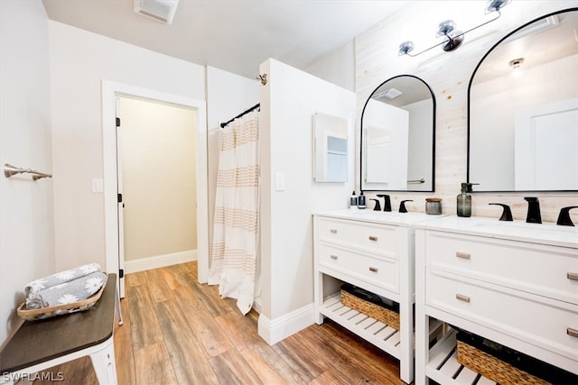 bathroom with double sink, oversized vanity, and wood-type flooring