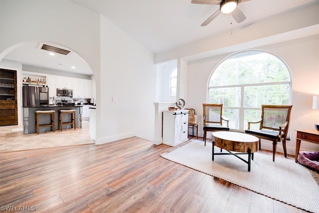 living area featuring high vaulted ceiling, light hardwood / wood-style floors, and ceiling fan