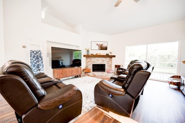 living room featuring light hardwood / wood-style floors, a fireplace, ceiling fan, and lofted ceiling