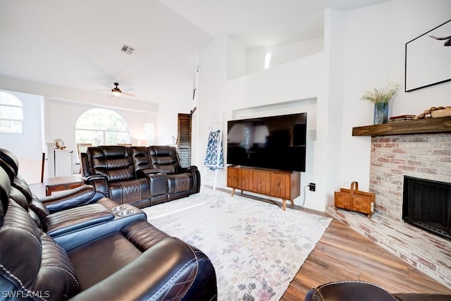 living room featuring lofted ceiling, light hardwood / wood-style floors, ceiling fan, and a fireplace