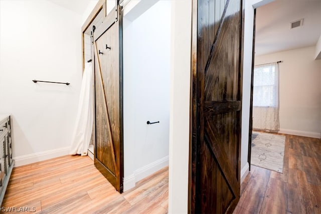 hallway featuring a barn door and light hardwood / wood-style flooring