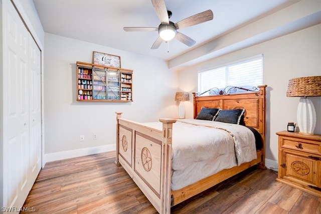 bedroom with dark hardwood / wood-style flooring, a closet, and ceiling fan