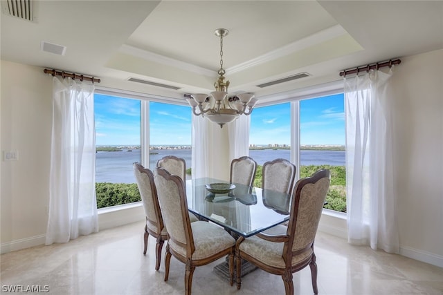 dining space with light tile patterned flooring, a water view, a chandelier, and a raised ceiling