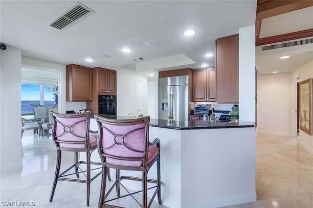 kitchen featuring dark stone counters, oven, visible vents, and high end refrigerator