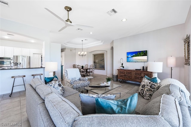 tiled living room with ceiling fan with notable chandelier and sink