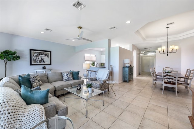 tiled living room with ceiling fan with notable chandelier