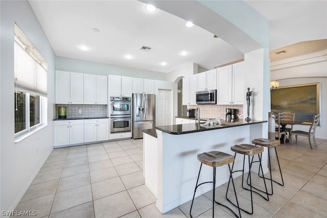 kitchen featuring white cabinets, a kitchen breakfast bar, tasteful backsplash, kitchen peninsula, and stainless steel appliances