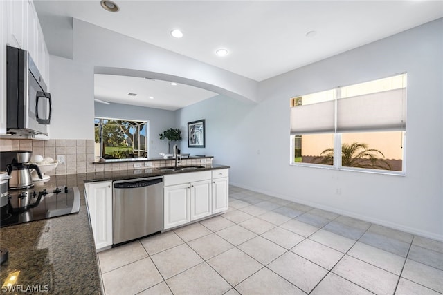 kitchen with decorative backsplash, appliances with stainless steel finishes, dark stone counters, sink, and white cabinets