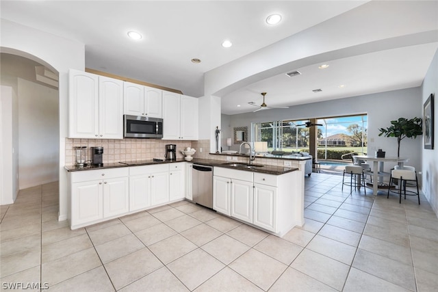 kitchen with ceiling fan, sink, stainless steel appliances, kitchen peninsula, and white cabinets