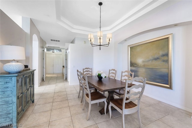 tiled dining room with a raised ceiling and an inviting chandelier