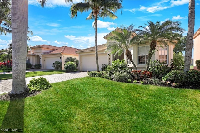 mediterranean / spanish home featuring a garage and a front lawn