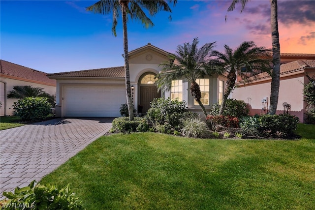 mediterranean / spanish house featuring a garage and a yard