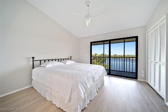 bedroom featuring a closet, a water view, access to outside, light hardwood / wood-style flooring, and lofted ceiling