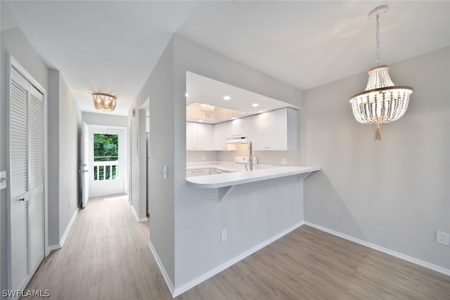 kitchen featuring white cabinetry, a chandelier, pendant lighting, stove, and light hardwood / wood-style flooring