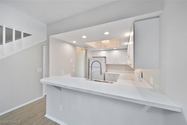 kitchen with range, light wood-type flooring, sink, and kitchen peninsula