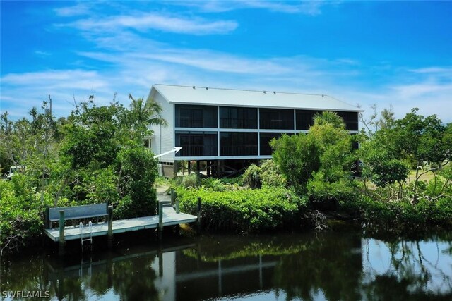 back of property with a water view and a sunroom