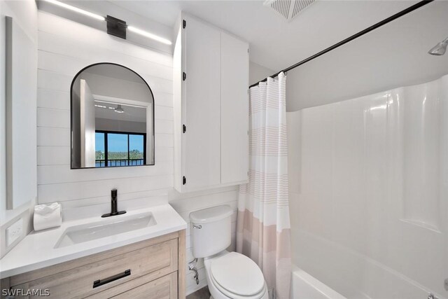 full bathroom with shower / bath combo with shower curtain, toilet, and vanity