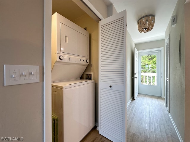 laundry room featuring stacked washer / dryer and light wood-type flooring