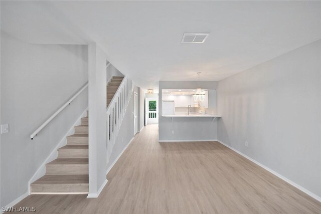 unfurnished living room with light hardwood / wood-style flooring and sink