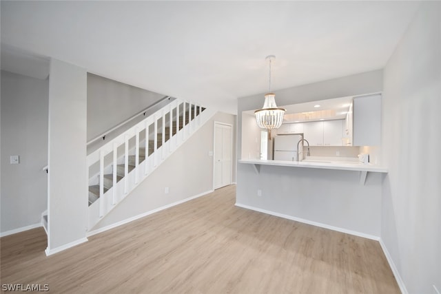 unfurnished living room with an inviting chandelier and light wood-type flooring