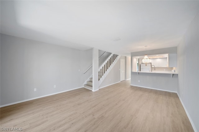 unfurnished living room featuring light hardwood / wood-style flooring and sink