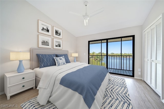 bedroom with a closet, light hardwood / wood-style flooring, a water view, and access to exterior