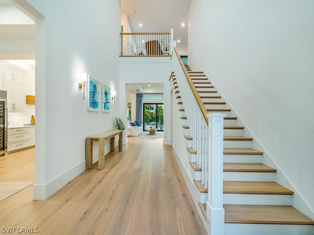 staircase with a towering ceiling and wood-type flooring