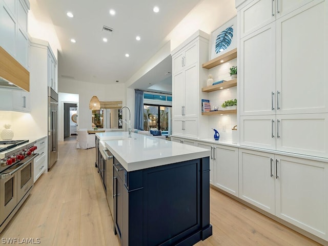 kitchen with white cabinetry, a center island with sink, and premium appliances