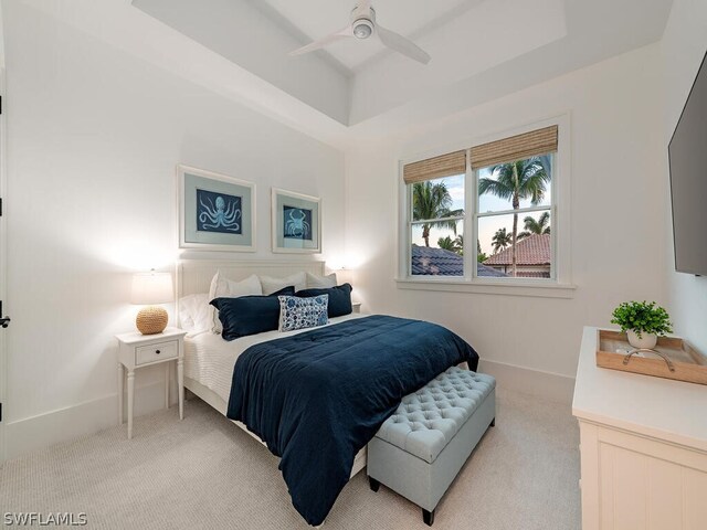 carpeted bedroom featuring ceiling fan and a raised ceiling