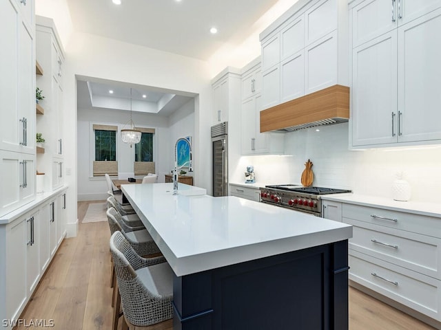 kitchen with a center island with sink, hanging light fixtures, and stove