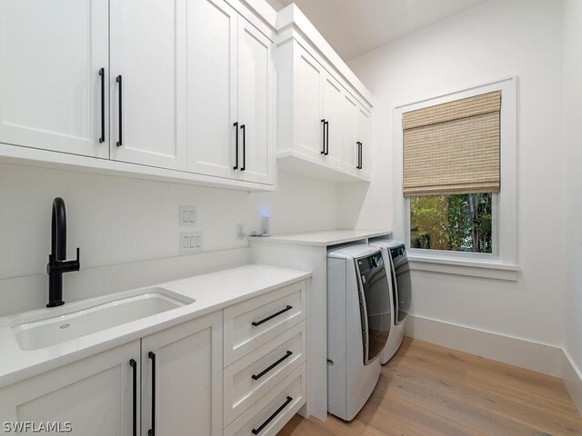 laundry area featuring cabinets, washer and clothes dryer, sink, and light hardwood / wood-style flooring