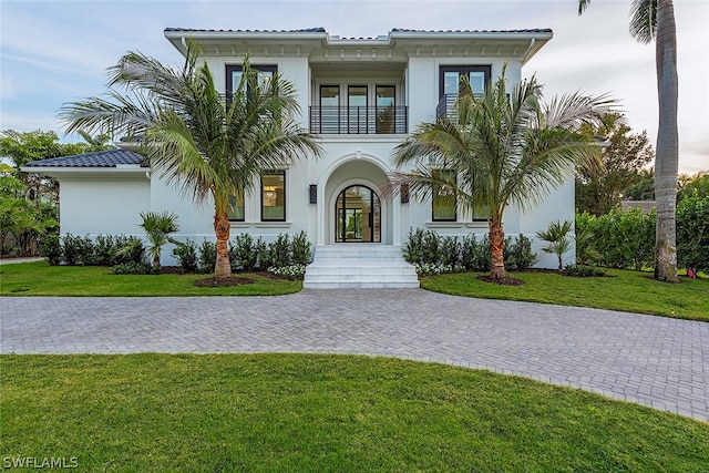 mediterranean / spanish-style home with a front yard, french doors, and a balcony