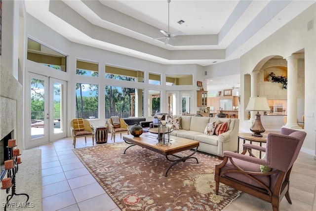 living room with french doors, a towering ceiling, ceiling fan, and decorative columns