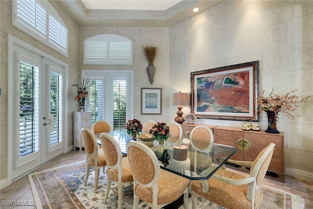 dining space featuring tile walls, a high ceiling, and french doors