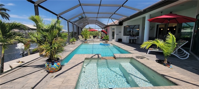 view of pool featuring a patio, an in ground hot tub, and glass enclosure