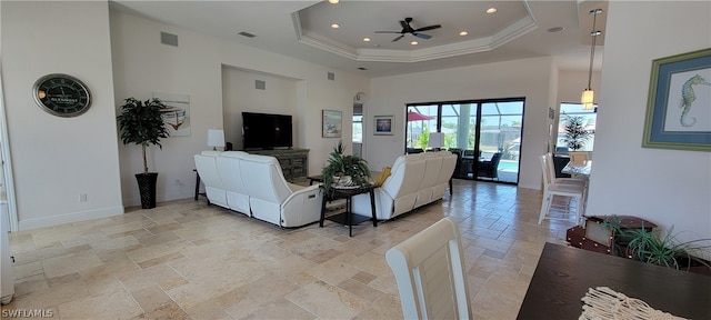 living room with a raised ceiling, ceiling fan, light tile floors, and a high ceiling