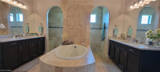 bathroom with tile walls, dual bowl vanity, and a bath