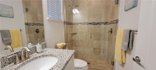 bathroom featuring vanity, a shower with shower door, and toilet