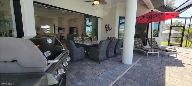 view of terrace with grilling area, ceiling fan, glass enclosure, and exterior kitchen