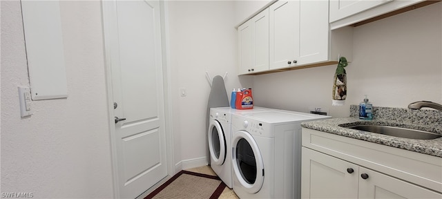 washroom featuring washing machine and dryer, cabinets, and sink