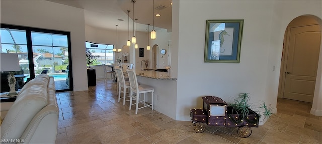 kitchen featuring a kitchen breakfast bar, light tile floors, decorative light fixtures, light stone countertops, and an inviting chandelier