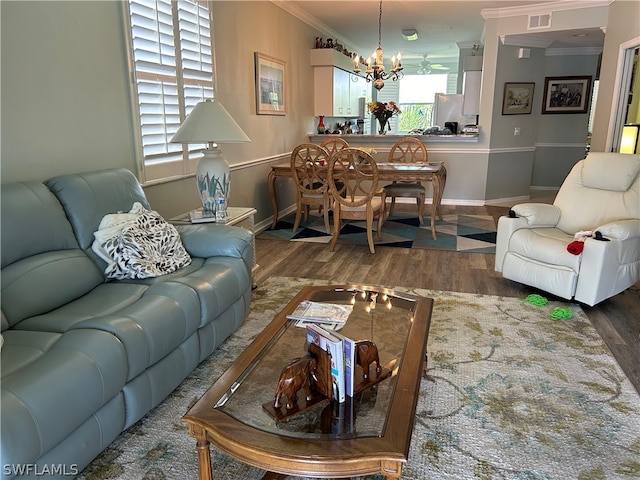 living room with an inviting chandelier, dark hardwood / wood-style floors, and ornamental molding