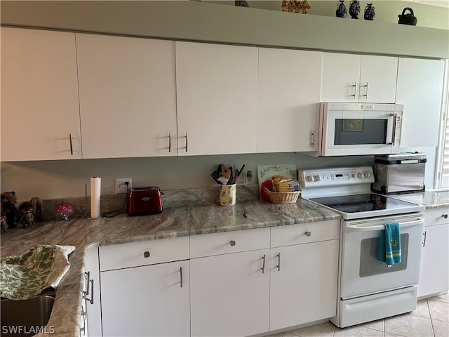 kitchen featuring white appliances, white cabinets, and light tile floors