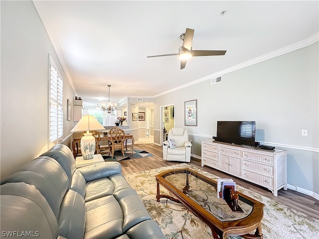 living room featuring crown molding, wood-type flooring, and ceiling fan with notable chandelier