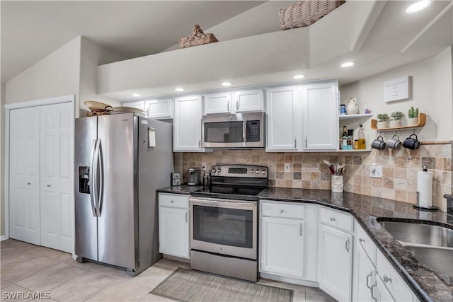 kitchen featuring dark stone counters, stainless steel appliances, white cabinetry, and open shelves