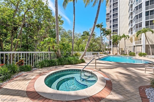 pool featuring a community hot tub, a patio, and fence